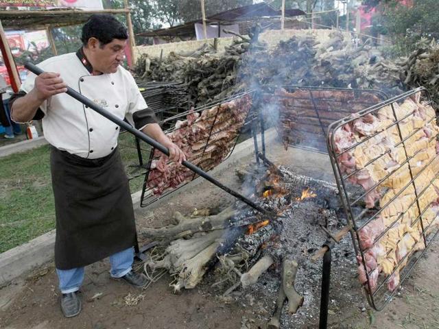 A worker cooks the Peruvian pork dish, 'chancho al palo,' during the IV edition of the Peruvian International Gastronomic Fair 'Mistura' in Lima, Peru.