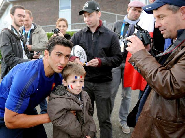 France’s rugby union center Maxime Mermoz (L) poses with a young supporter for a picture after a team training session at the Takapuna Rugby Club in Auckland.