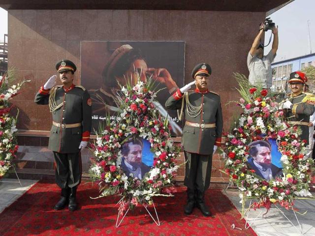 An honour guard of Afghan security personnel salute as they stand beside a floral tribute during a ceremony marking the tenth anniversary of the death of slain Afghan national hero Ahmad Shah Masood in Kabul.