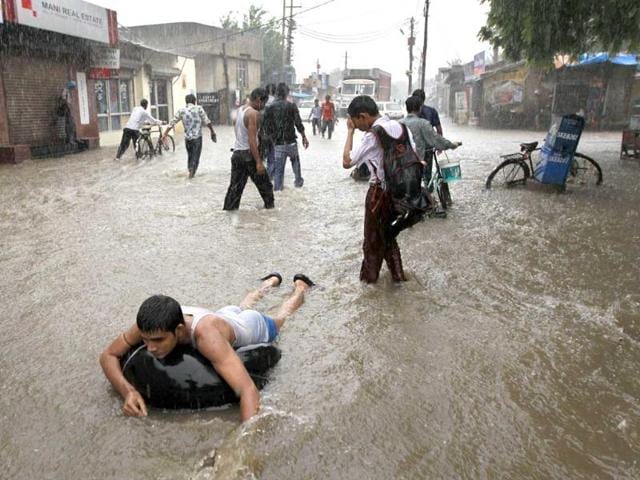 A local enjoys the rain floating on an inflated tube while others negotiate a flooded street after heavy monsoon rains in New Delhi.