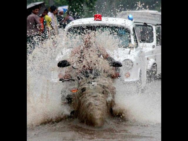 A man rides his bike through a flooded road during heavy rains in New Delhi.