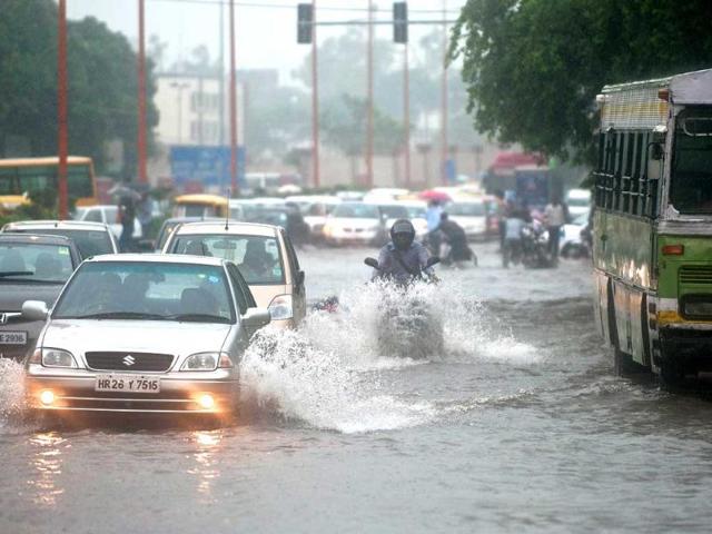 Office-goers travel through a water-clogged road following heavy rainfall in New Delhi.