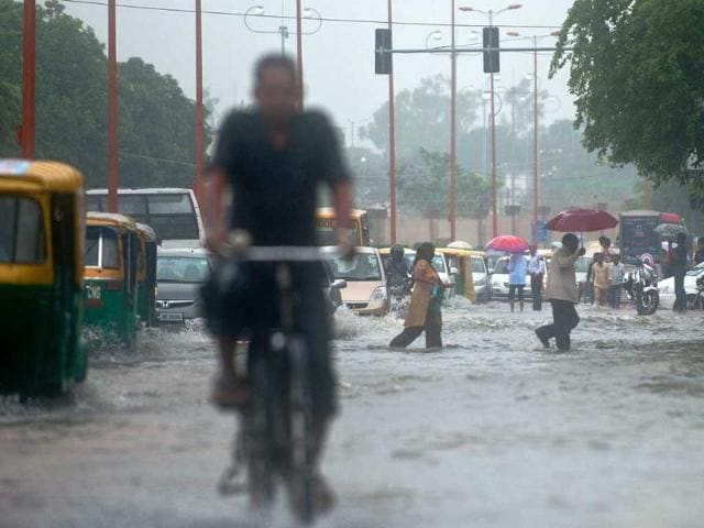 Office-goers wade through a water-clogged road following heavy rainfall in New Delhi.