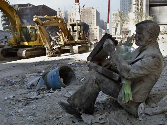 A dust covered bronze statue of a man with his briefcase rests in the rubble of the World Trade Center on 13 September 2001, in New York. The statue once rested on a bench near the towers and now holds flowers and a note reading "In memory of all who gave their lives and tried to save so many". File photo