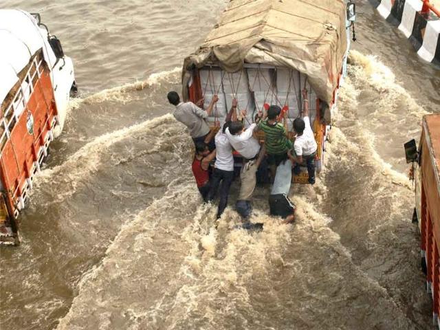 Boys hang on to a loaded truck moving through a flooded road after the heavy downpour in New Delhi.