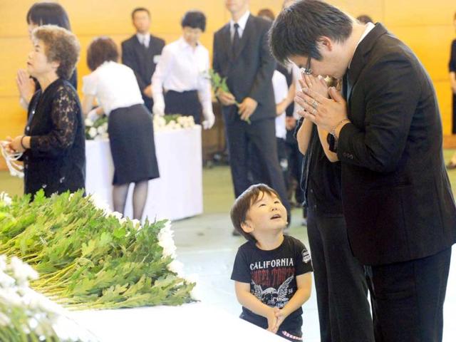 A young resident attends a memorial service for the victims of the March 11 earthquake and tsunami at Soma, Japan.