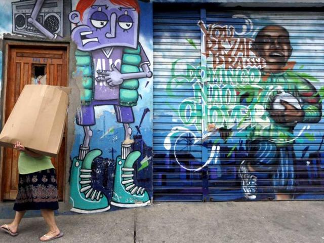 A woman carries a box as she walks past graffiti painted by Brazilian artist Chivitiz working with OPNI, an organization that uses graffiti to improve life in the slums, in the Vila Flavia favela of Sao Paulo.