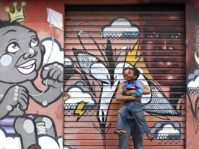 A man jokes with Ryan, 6, in front of graffiti painted by artists working with OPNI, an organization that uses graffiti to improve life in the slums, in the Vila Flavia favela of Sao Paulo.