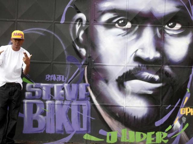 Rapper Skip, 20, poses in front of a graffiti of South African black activist Steven Biko painted by Brazilian artists working with OPNI, an organization that uses graffiti to improve life in the slums, in the Vila Flavia favela of Sao Paulo.