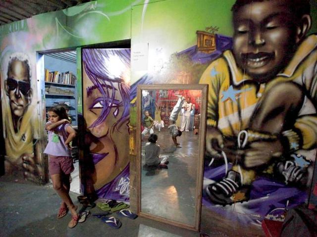 Children performing a capoeira dance are reflected in a mirror as a girl watches at Sao Mateus em Movimento, the headquarters of OPNI, an organization that uses graffiti to improve life in the slums, in the Vila Flavia favela of Sao Paulo.