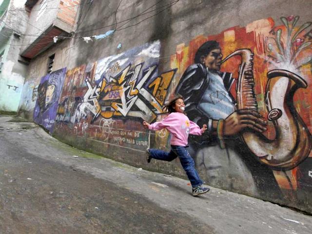A girl runs next to graffiti painted by Spanish artist Sato by invitation from OPNI, an organization that uses graffiti to improve life in the slums, in the Vila Flavia favela of Sao Paulo.