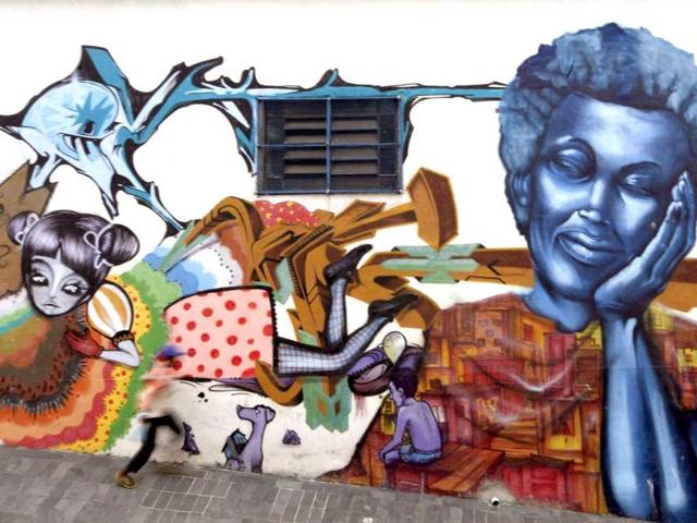 A child runs in front of graffiti painted by Brazlian artists Nem, Tika, Malmeks, Quinho, Joao and members of OPNI, an organization that uses graffiti to improve life in the slums, in the Vila Flavia favela of Sao Paulo.
