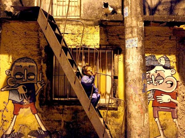 A child sits on stairs of a house next to graffiti painted by Brazilian artist Chivitiz, a member of OPNI, an organization that uses graffiti to improve life in the slums, in the Vila Flavia favela of Sao Paulo.