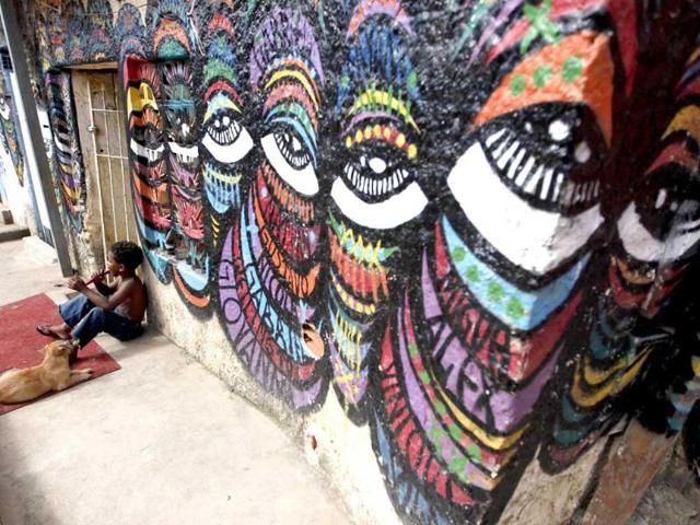 A child sits with his dog next to graffiti painted by artists of OPNI, an organization that uses graffiti to improve life in the slums, in the Vila Flavia favela of Sao Paulo.