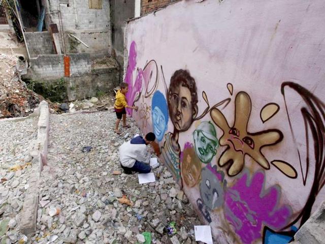 Students of OPNI, an organization that uses graffiti to improve life in the slums, paint a wall during a graffiti class in the Vila Flavia favela of Sao Paulo.