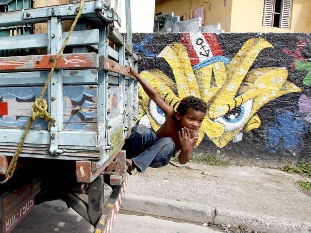 Ryan, 6, climbs onto a truck carrying oranges in front of graffiti painted by artists of OPNI, an organization that uses graffiti to improve life in the slums, in the Vila Flavia favela of Sao Paulo.