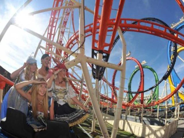 A group of TV presenters pose for a photo in traditional Bavarian dresses (Dirndl) at a rollercoaster ride at the Theresienwiese fair ground of the Oktoberfest beer festival in Munich.
