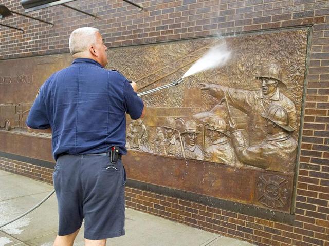 A fireman washes a memorial for firefighters on the wall of a station near the World Trade Center in New York.