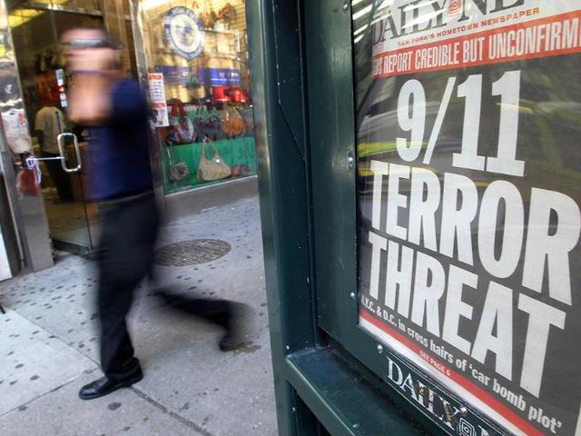 A man walks past a newspaper headline reading 9/11 Terror Threat in Manhattan in New York City.