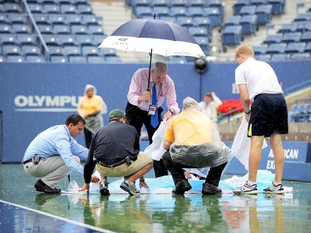 Workers cover a painted sign commemorating the 10th anniversary of 9/11 terror attacks on the court as rainfall delays the Men's semifinal match between Novak Djokovic of Serbia and Roger Federer of Switzerland at the US Open tennis tournament.