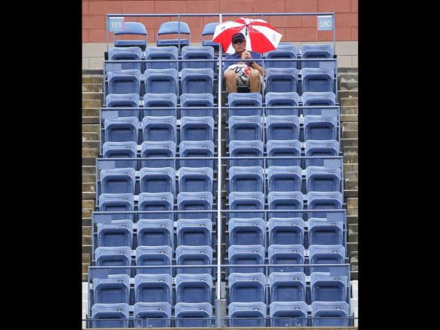 A patron waits in the rain for the start of a semifinal match at the US Open tennis tournament in New York.