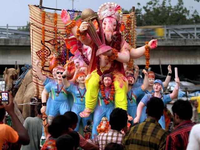 An idol of elephant-headed God Ganesha, depicted as seated on the shoulders of Indian cricketer Sachin Tendulkar as other cricketers cheer, is taken for immersion in the River Sabarmati on the ninth day of the Ganesh Chaturthi festival in Ahmadabad.