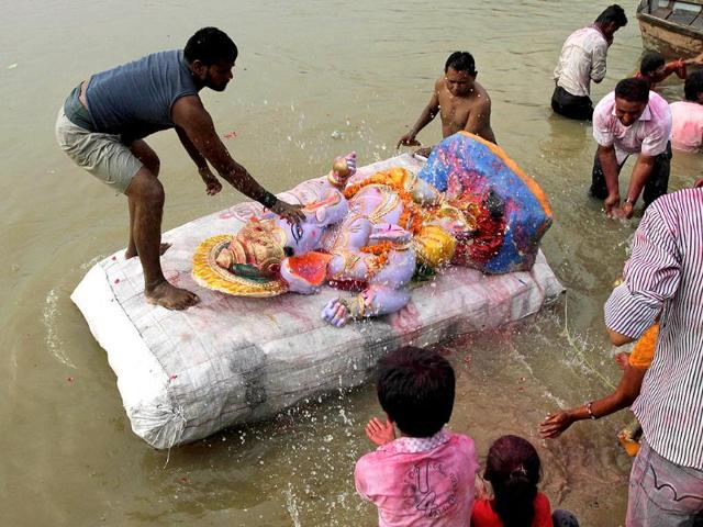 Hindu devotees sprinkle water on an idol of elephant-headed Hindu God Ganesh before its immersion in the River Sabarmati during Ganesh Chaturthi festival in Ahmadabad.