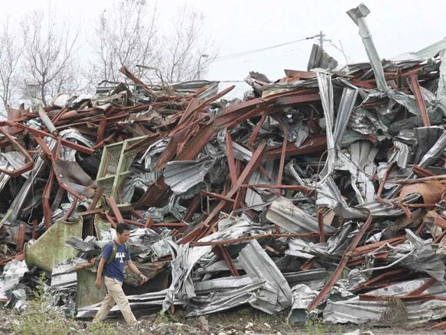 A man walks near a pile of tsunami debris in Ishinomaki, Miyagi Prefecture, six months after the area was devastated by a 9.0 magnitude earthquake and tsunami.