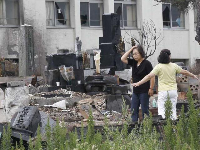 Masuno (L) reacts as she looks around her family's tomb which was damaged by March 11's 9.0 earthquake and tsunami, in Ishinomaki, Miyagi Prefecture, six months after the disaster.