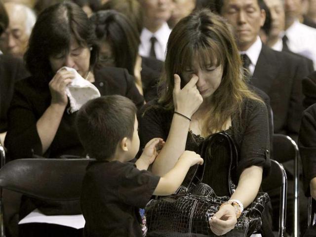Participants cry after observing a minute of silence for victims of the March 11 earthquake and tsunami during a memorial service in Minamisanriku town, Miyagi prefecture.