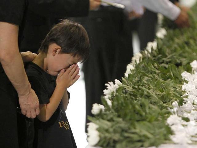 A boy prays for victims of the March 11 earthquake and tsunami after offering a flower during a memorial service in Minamisanriku town, Miyagi prefecture.