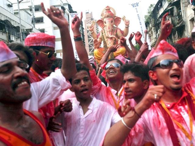 Devotees covered in coloured powder dance and sing as they carry an idol of Lord Ganesha during a procession before immersing it in the waters of the Arabian Sea on the last day of the Ganesh Chaturthi festival in Mumbai.