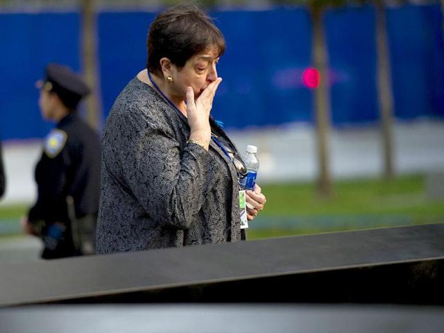 A woman kisses the memorial wall on the North Tower reflecting pool of the 9/11 Memorial in New York.