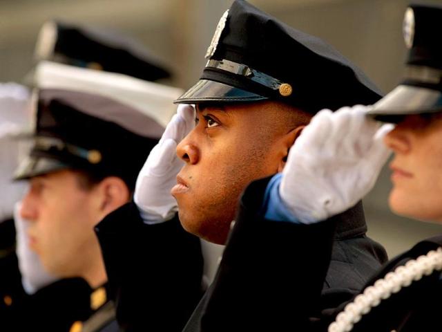 New York police, firefighters and Port Authority police salute during singing of the Star Spangled Banner at one of the entrances of 9/11 Memorial Plaza in New York City.