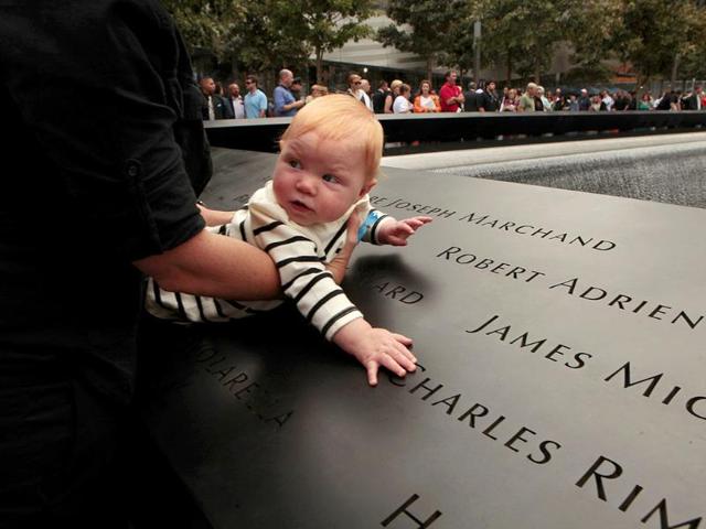 Julie Jalbert-Pitt, who's father, Robert Adrien Jalbert, was killed at the World Trade Center, holds her 8-month-old daughter, Campbell Pitt, next to the name of her father during a ceremony marking the 10th anniversary of the attacks Sunday, Sept. 11, 2011, in New York.