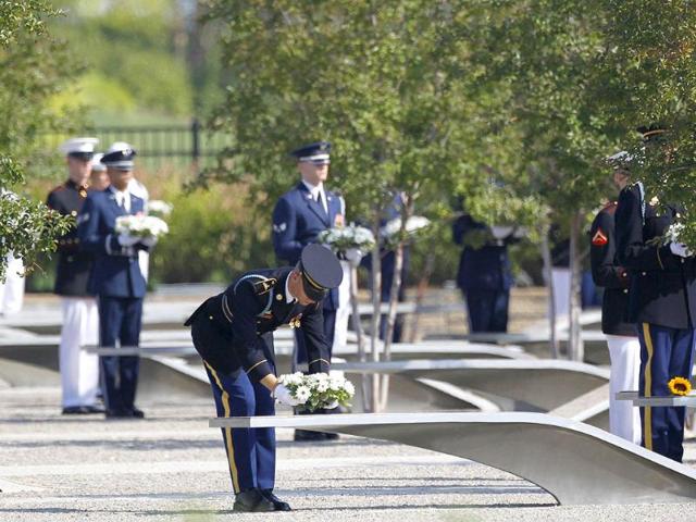 Military personnel distribute wreaths for each victim of the attack on the Pentagon, among the commemorative benches in the memorial for the victims, during ceremonies marking the 10th anniversary of the 9/11 attack on the Pentagon, in Washington