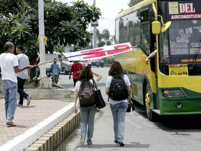 A protester uses his organization's banner to provide a shade to a couple of female commuters as they walk towards their ride on a hot weather in Manila, Philippines.