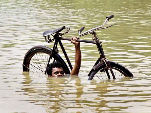 A villager wades through flooded water carrying his bicycle near Megha village, 55 kilometers from Bhubaneswar.