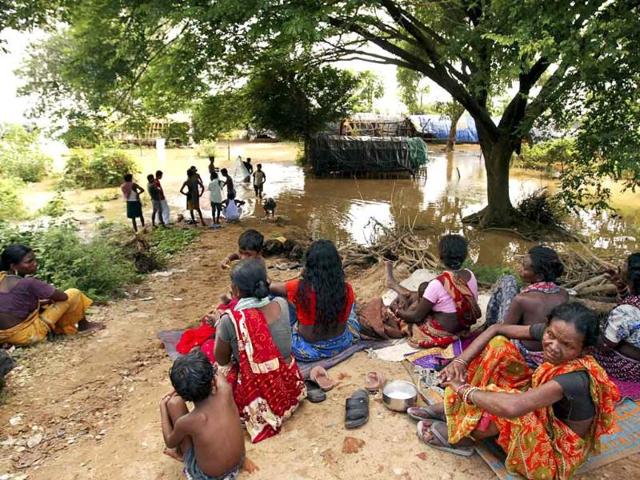 Villagers sit on dry land after their homes were flooded by the rising waters of the River Mahanadi on the outskirts of Cuttack city, about 30 kilometers from Bhubaneshwar.