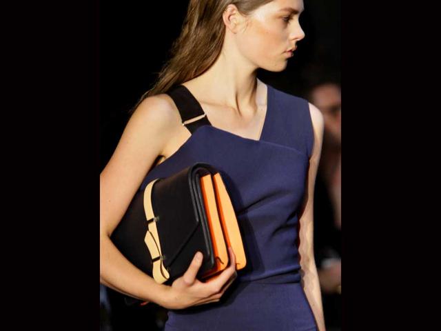 A model dons an orange and black clutch to go with the charcoal outfit.