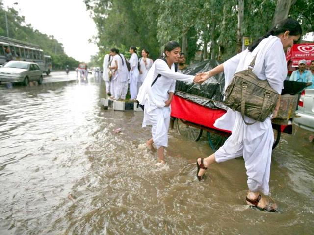 College girls wade through a flooded road after a heavy downpour in Jammu.