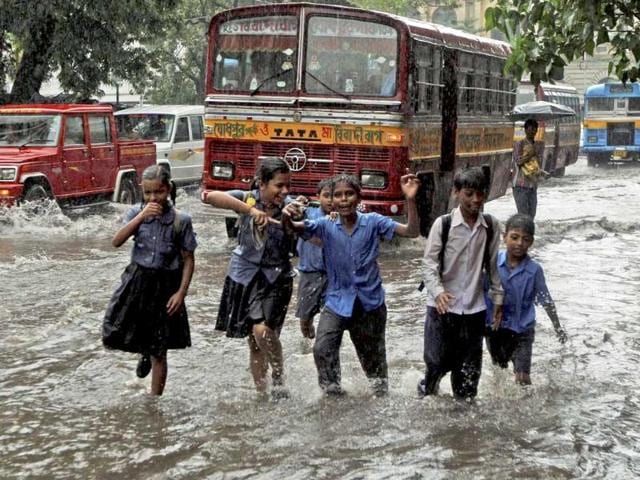 School students play on a waterlogged road as they return from school in Kolkata after heavy rain.