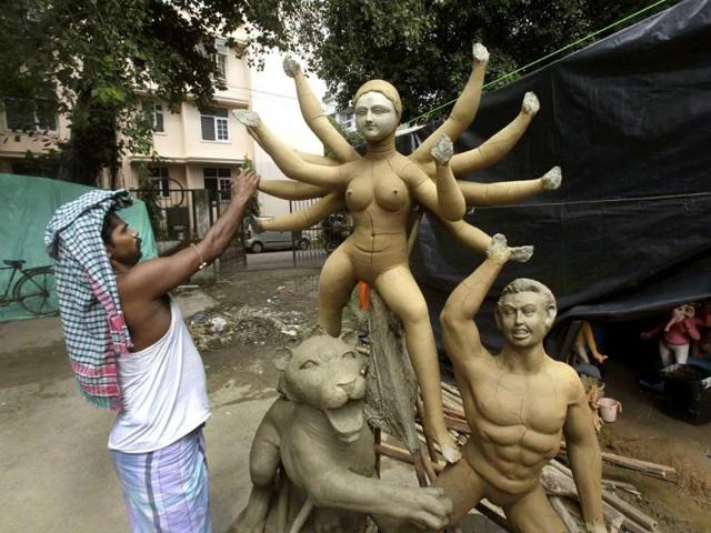 An artisan moulds the hand of an idol of Goddess Durga, ahead of the Durga Puja festival.