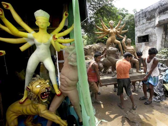 Artisans carry an idol of Goddess Durga to dry in the sun, ahead of the Durga Puja festival in New Delhi.