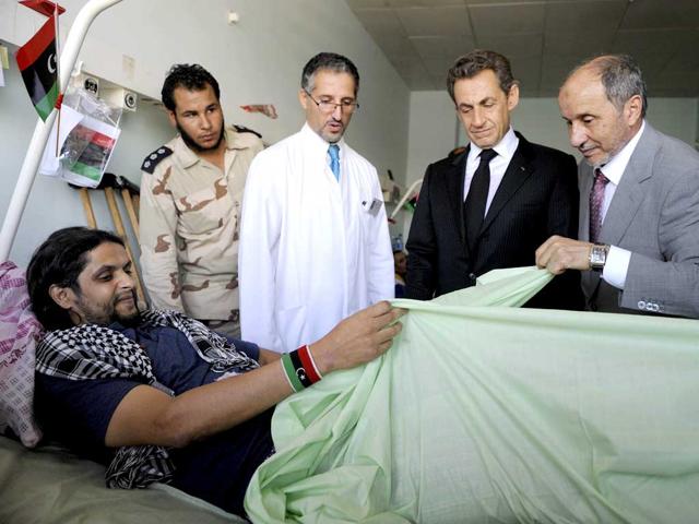 French President Nicolas Sarkozy (C) and National Transition Council President Mustafa Mohammed Abdul Jalil (R) visit injured people in the Tripoli Medical center.