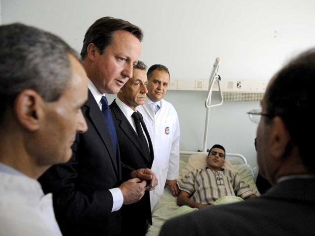 French President Nicolas Sarkozy, Britain's Prime minister David Cameron and National Transition Council Prime minister Mahmud Jibril (R) visit injured people in the Tripoli Medical center during their travel in Libya in Tripoli.