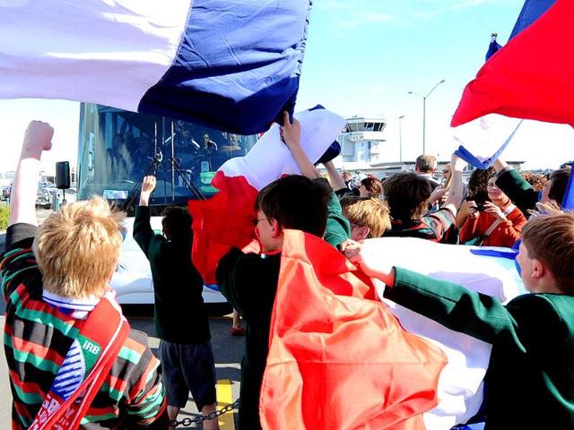Fans wave flags as the French team take the bus after their arrival at the Hawke's Bay airport in Napier during the 2011 Rugby World Cup.
