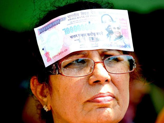 A supporter of the Bharatiya Janata Party (BJP) places a fake Indian bank note on her head, as she protests against petrol price hikes in New Delhi.