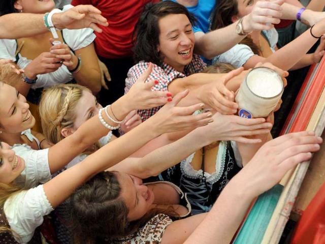 Visitors stretch to reach a beer mug in a festival tent of the Oktoberfest beer festival at the Theresienwiese ground in Munich, southern Germany. The 178th edition of the world's biggest beer festival kicked off today to run till October 3.
