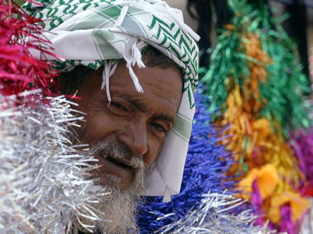 A man looks out from between truck decoration items kept for sale at a roadside in Noida.